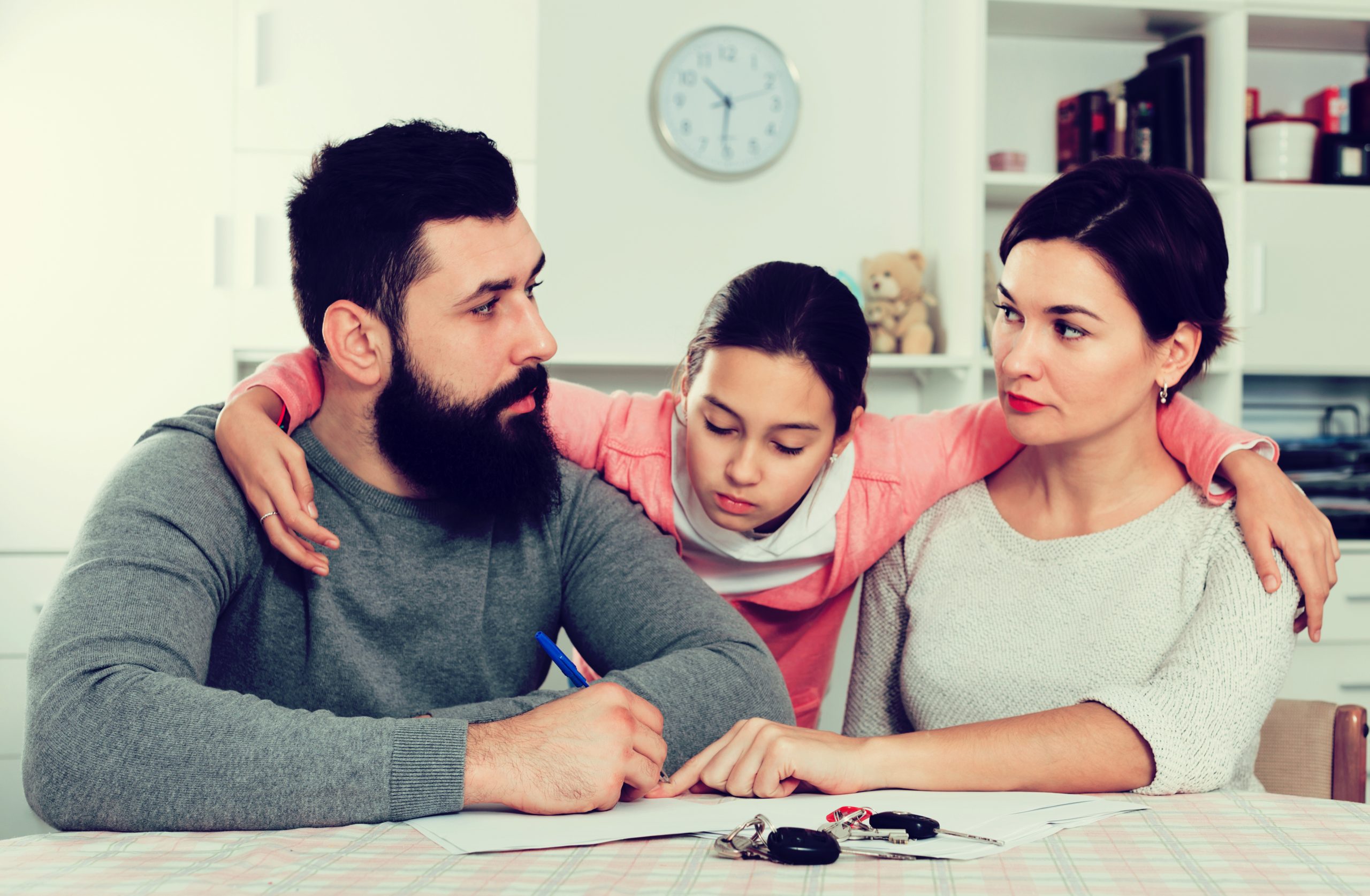 Young sad parents signing papers for divorce while their daughter at home interior