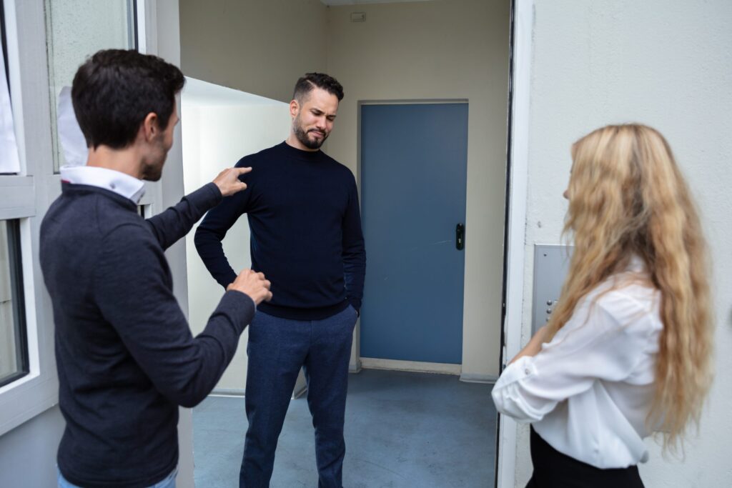 Rear View Of A Couple Quarreling With Man Standing Outside The Door