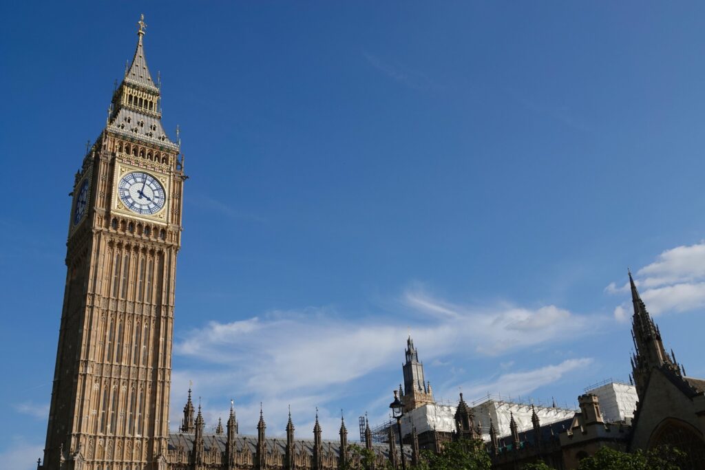Elizabeth Tower, known as Big Ben, rising into a blue sky above the Houses of Parliament in Westminster, London, UK.