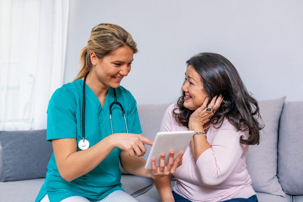 Happy young caregiver and senior woman using digital tablet together. Female nurse and senior woman using tablet PC. Elderly patient and nurse having fun with tablet