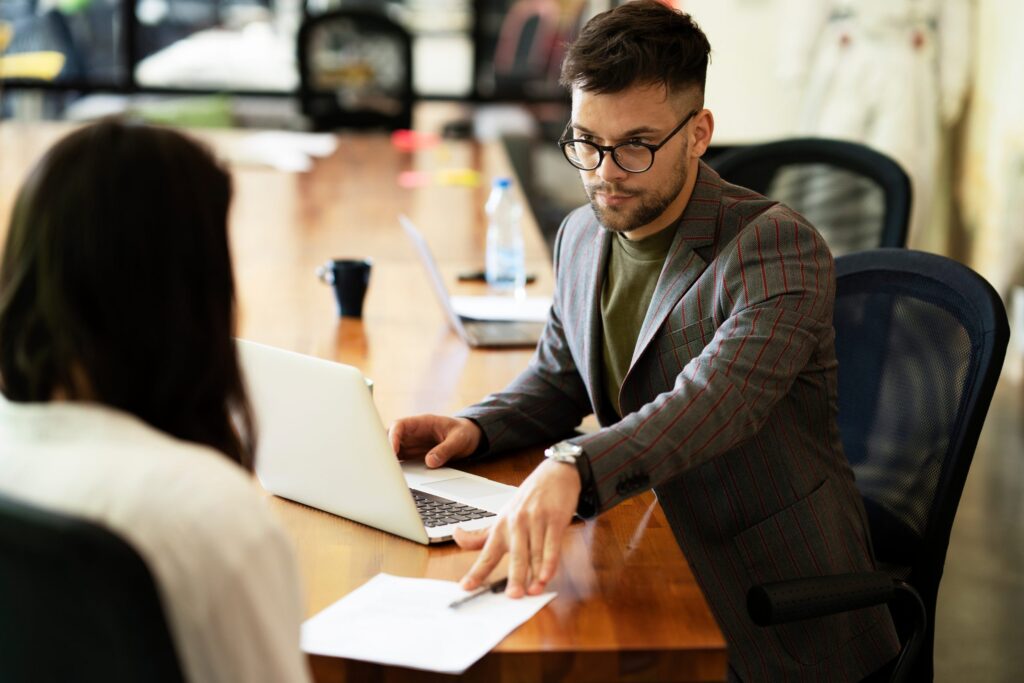 Businessman gives businesswoman dismissal contract to sign.
