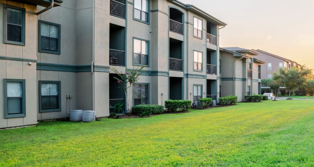 View from grassy backyard of a typical apartment complex building in suburban area at Humble, Texas, US. Sunset with warm light. Panorama style.