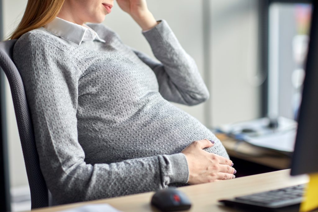 pregnancy, business, work and people concept - pregnant businesswoman sitting at office