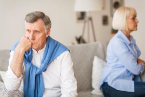 Senior couple after argument sitting on opposite sides of sofa