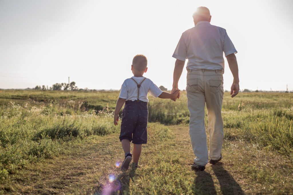 Happy child with Grandfather playing at the meadow. Grandpa retiree. Retirement parent