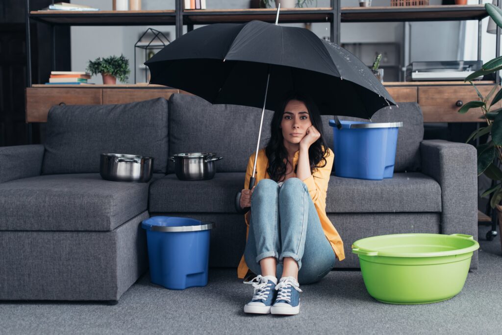 Woman with umbrella in house with a residential leak