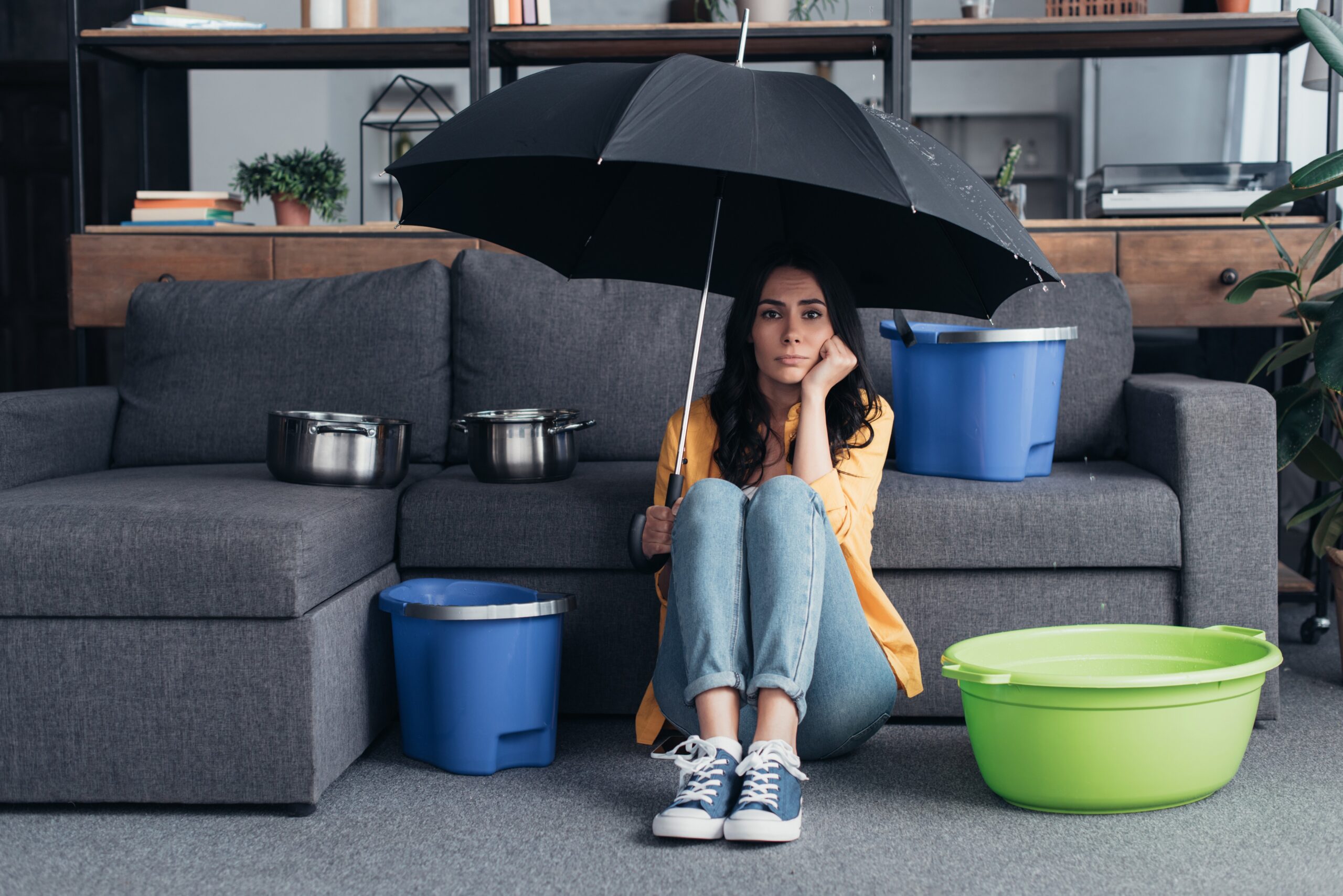 Woman with umbrella in house with a residential leak