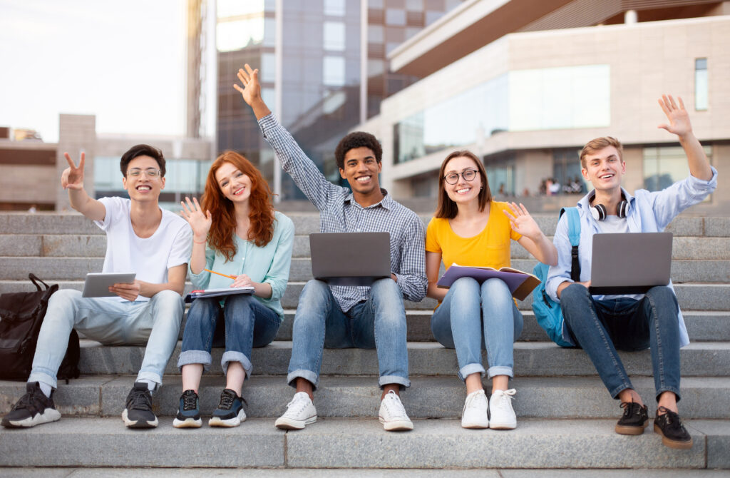 Multiracial students raising hands in the air and waving