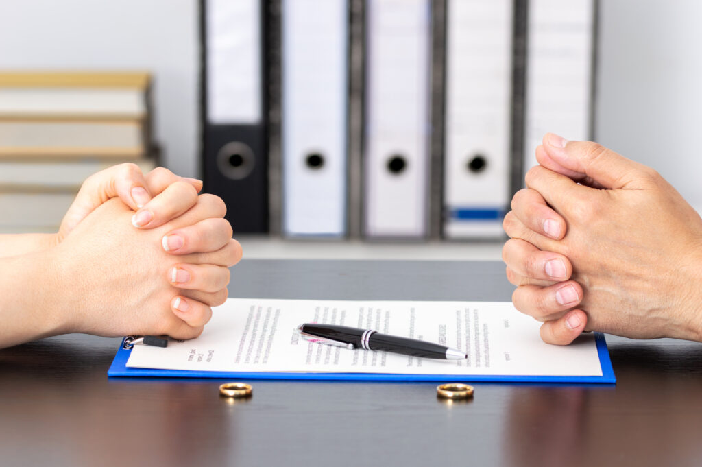 Hands of wife and husband signing divorce documents or premarital agreement at the lawyers office