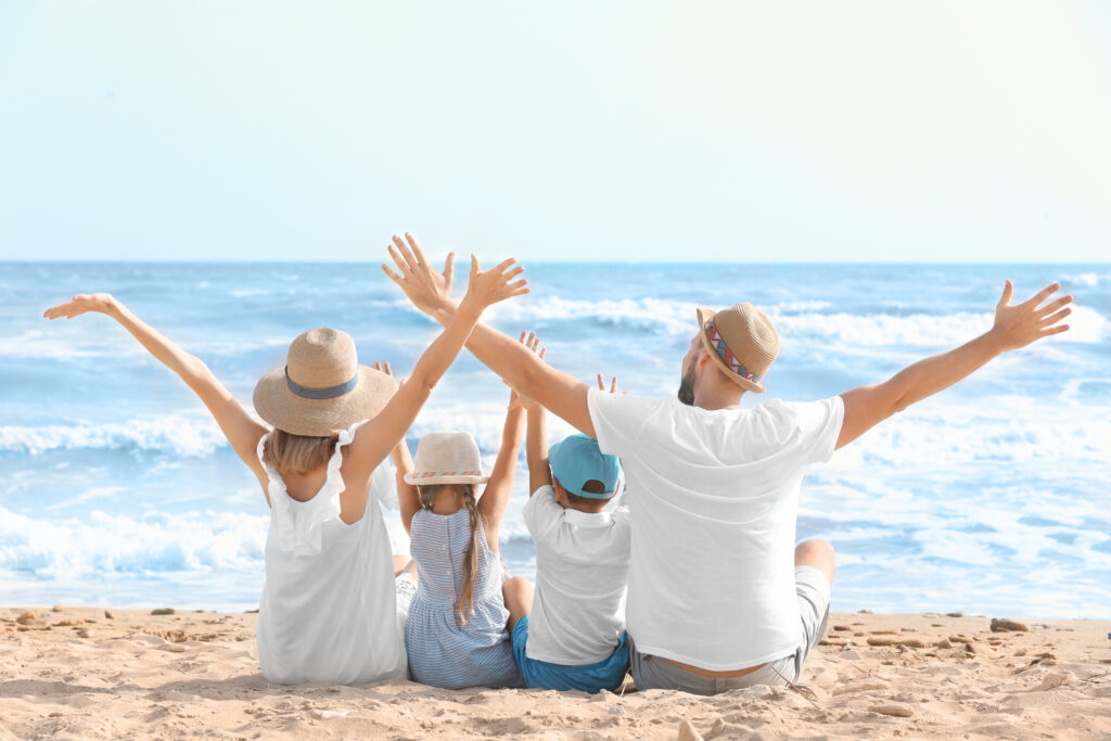 Happy family sitting on sea beach at resort