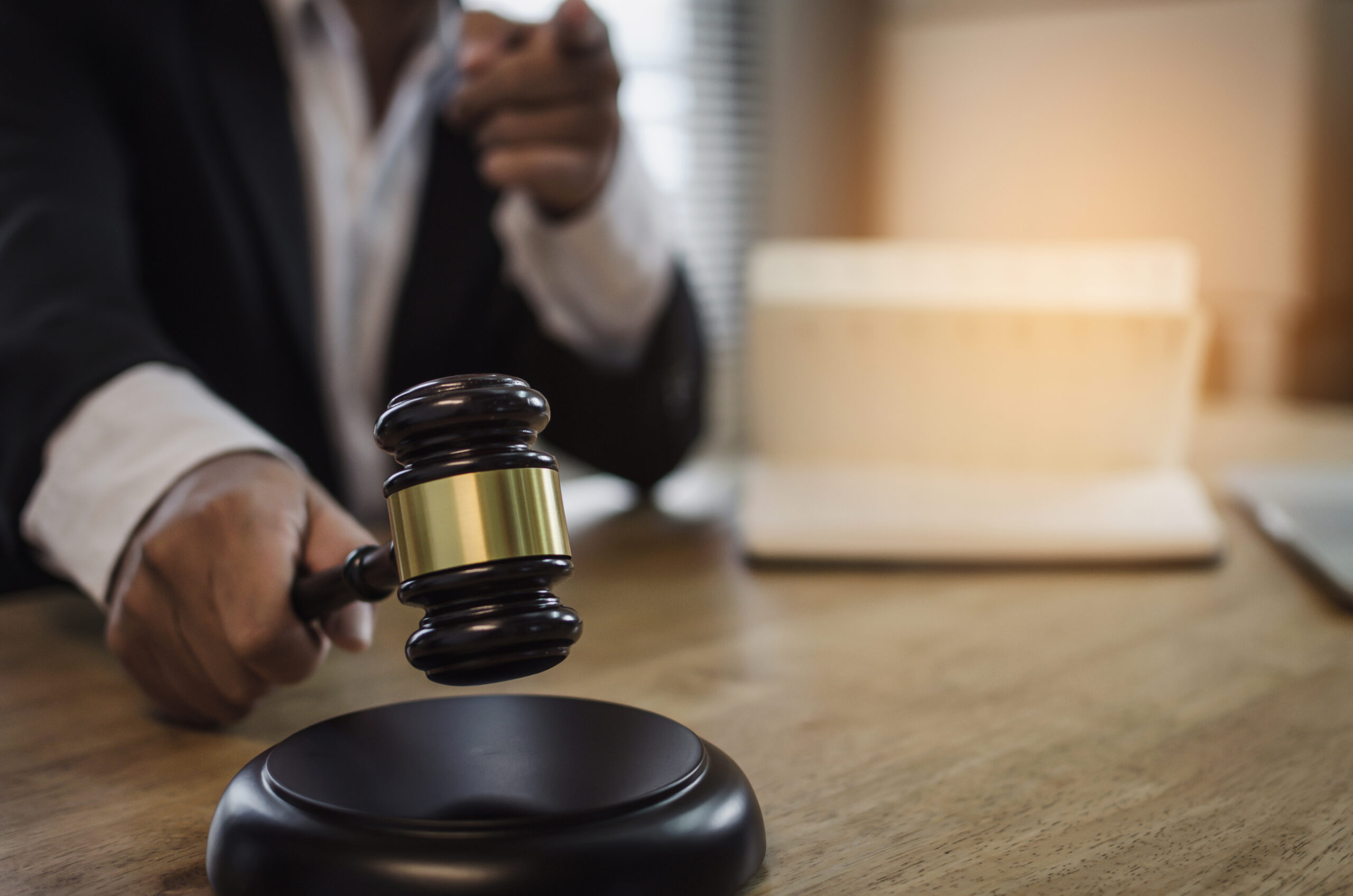 justice lawyer in black suit pointing finger and knocking wooden judge gavel with documents on workplace desk in courtroom office occupation business justice law and legal service concept