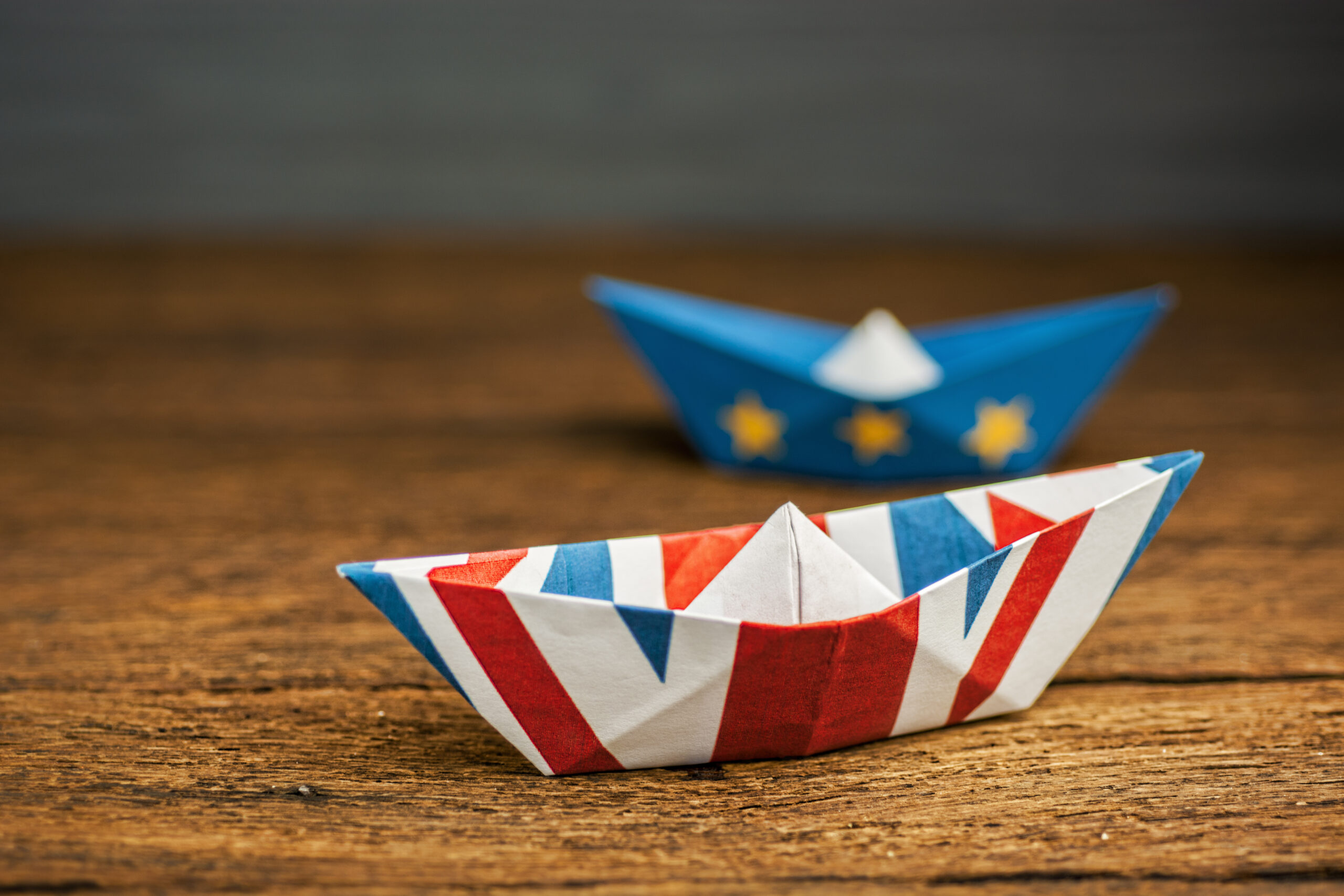 Brexit UK EU concept - paper ships from the flags of the European Union and the UK on a blue background