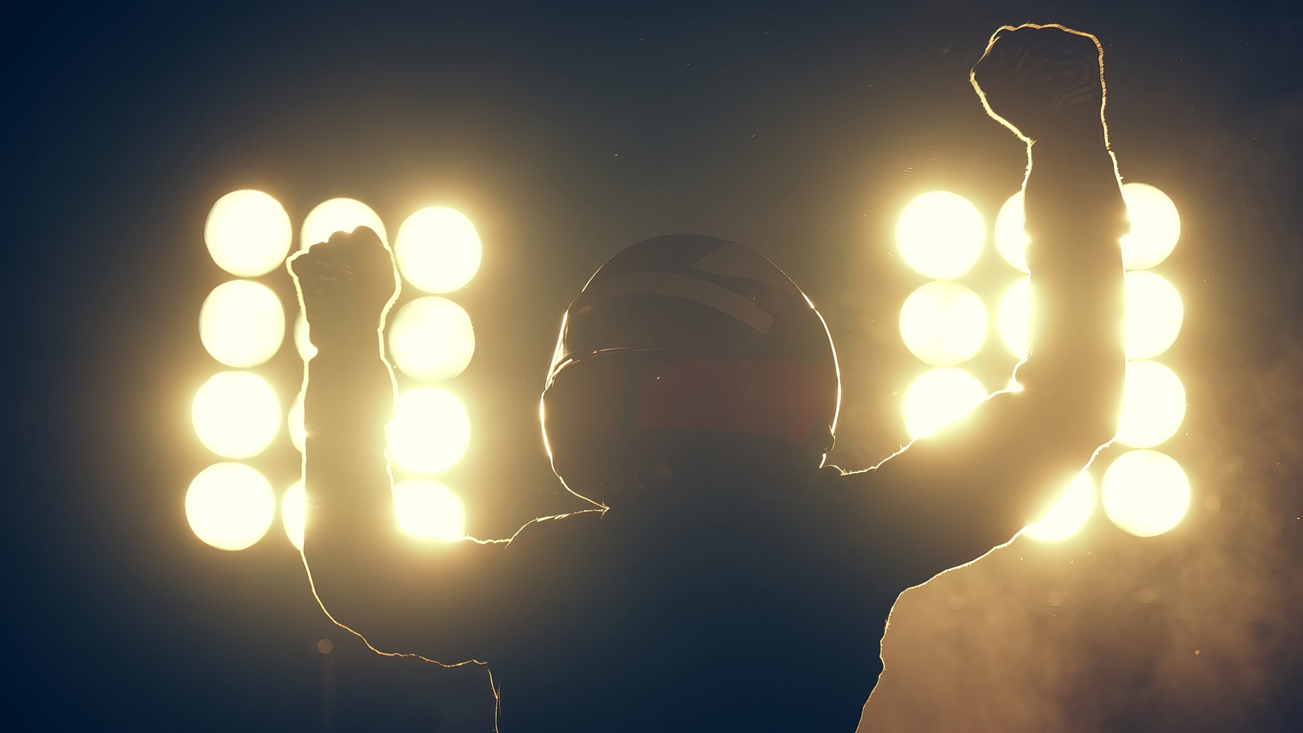Silhouette of race car driver celebrating the win in a race against bright light