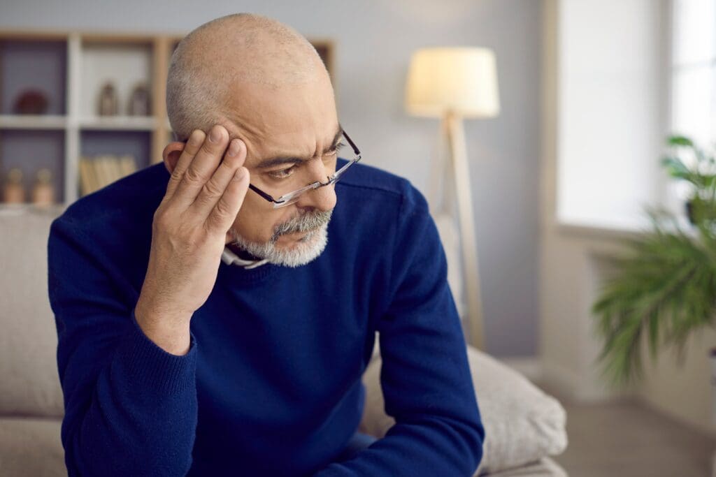 Older man with serious and thoughtful expression looks away thinking about something important.