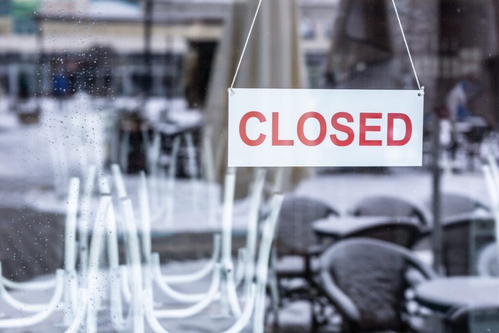 Sign saying closed hanging on the glass door of a restaurant or a bar