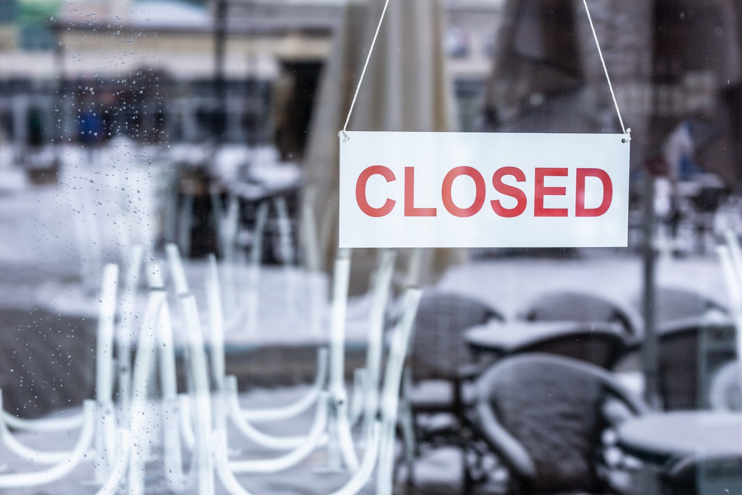 Sign saying closed hanging on the glass door of a restaurant or a bar