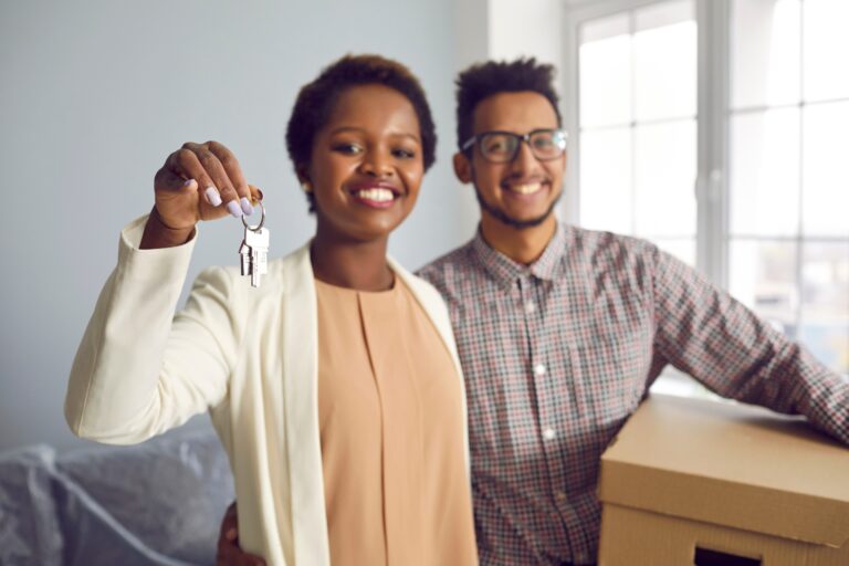 Close up focus portrait of excited multiracial couple buyers show keys moving to shared home together